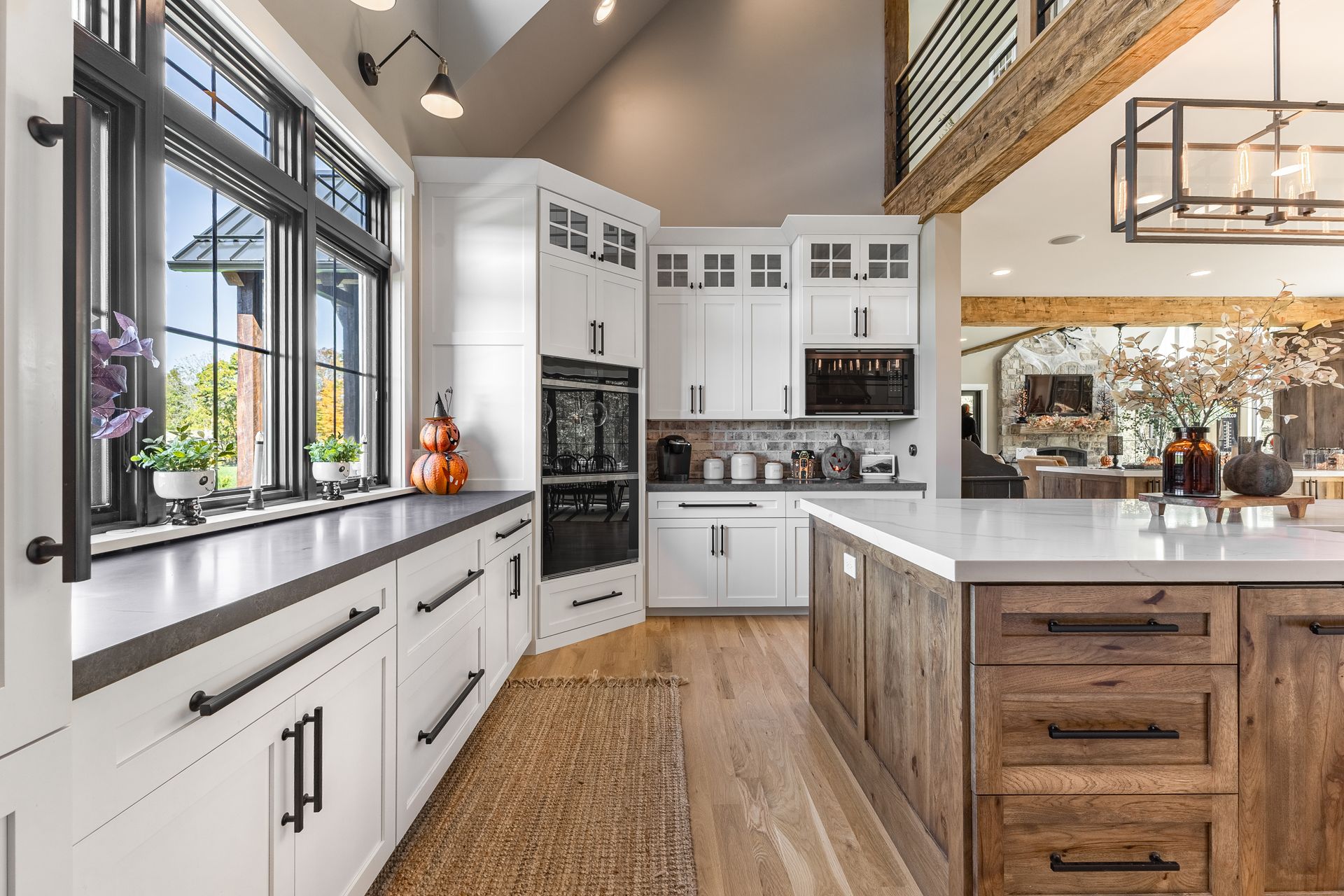 Bright kitchen with white cabinets, dark countertops, and a wood island. Large window with black trim.