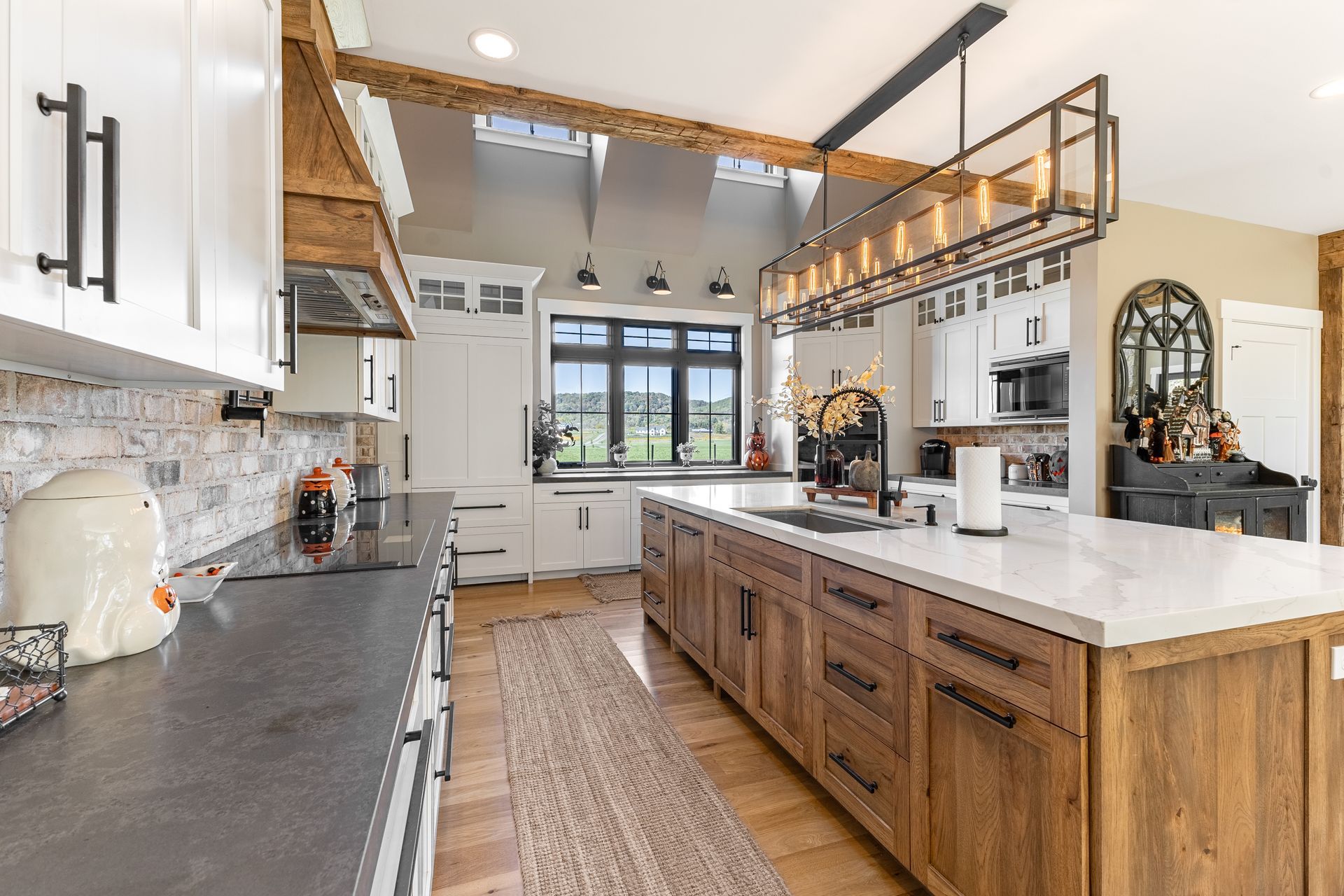 Spacious kitchen with wood island, white cabinets, and a long light fixture over the island.