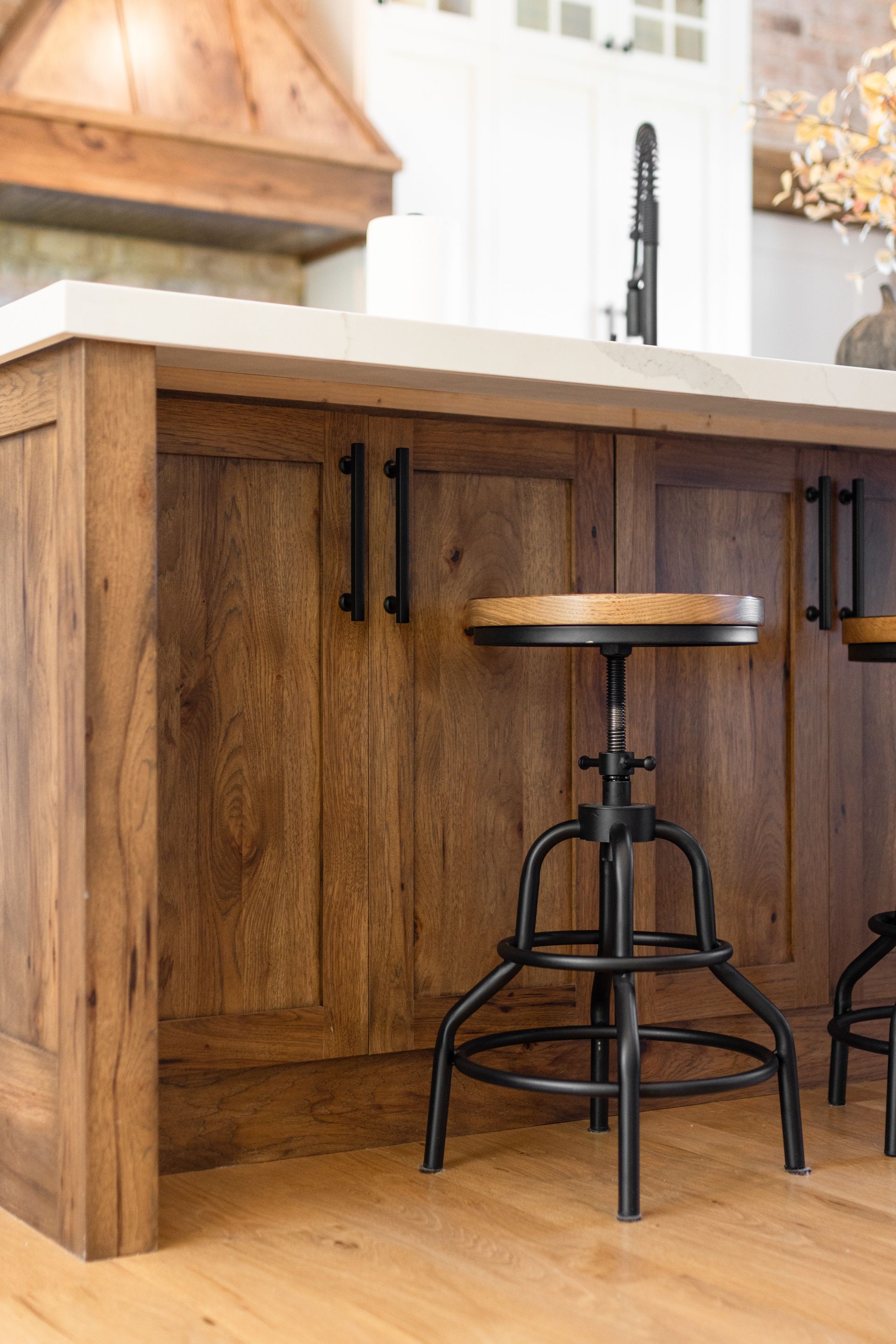 Wooden kitchen island with black hardware and adjustable stool.
