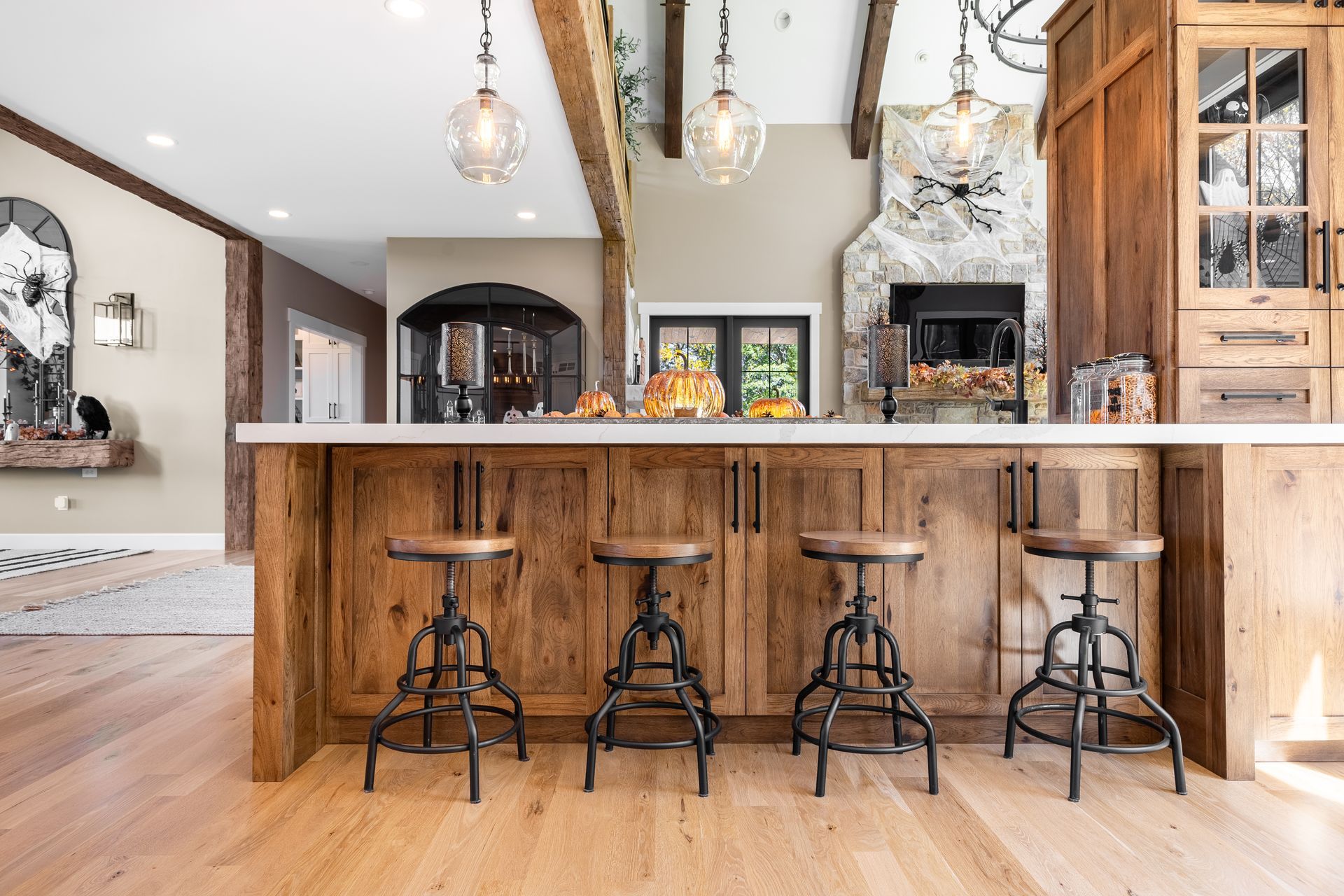 Rustic kitchen with wood island, stools, fireplace, and pendant lights.