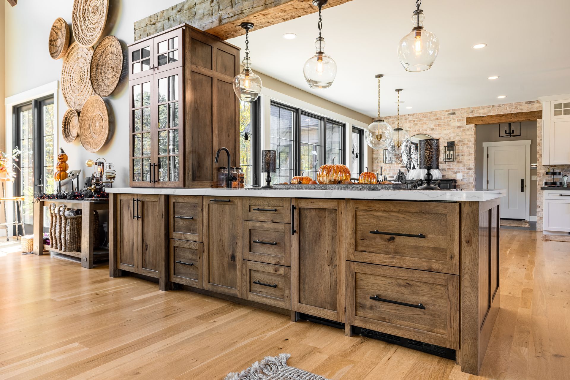 Rustic kitchen with wood island, cabinetry, and flooring; stone accents; and hanging globe lights.