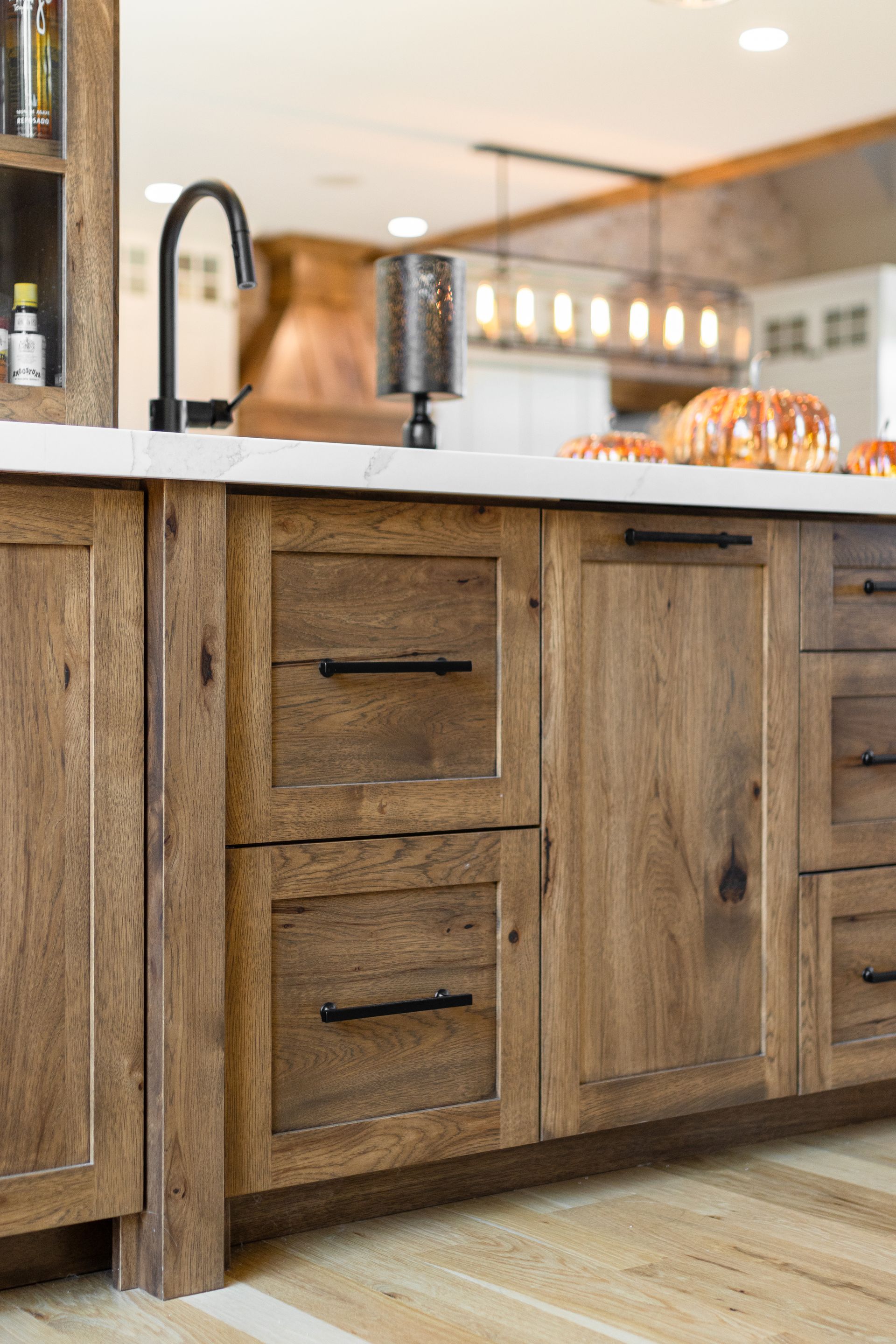Wooden kitchen cabinets with black hardware and a white countertop.