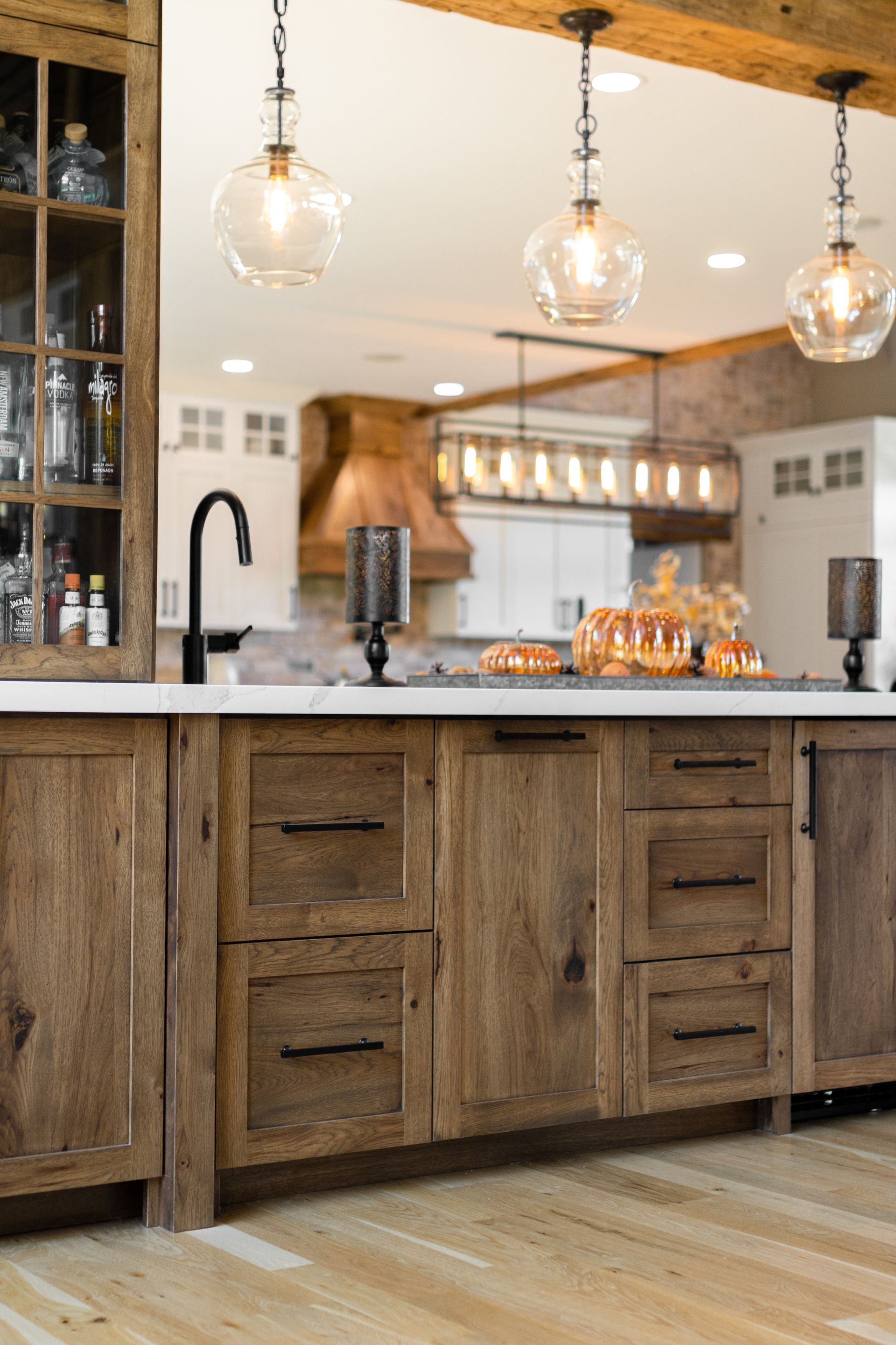 Rustic kitchen with wood cabinets, white countertops, and globe pendant lights.