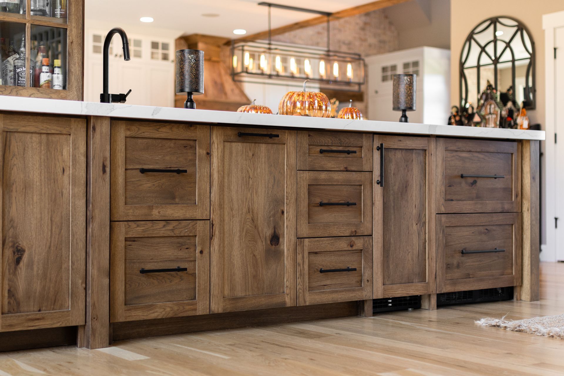 Rustic wooden kitchen cabinets with black hardware and a white countertop.