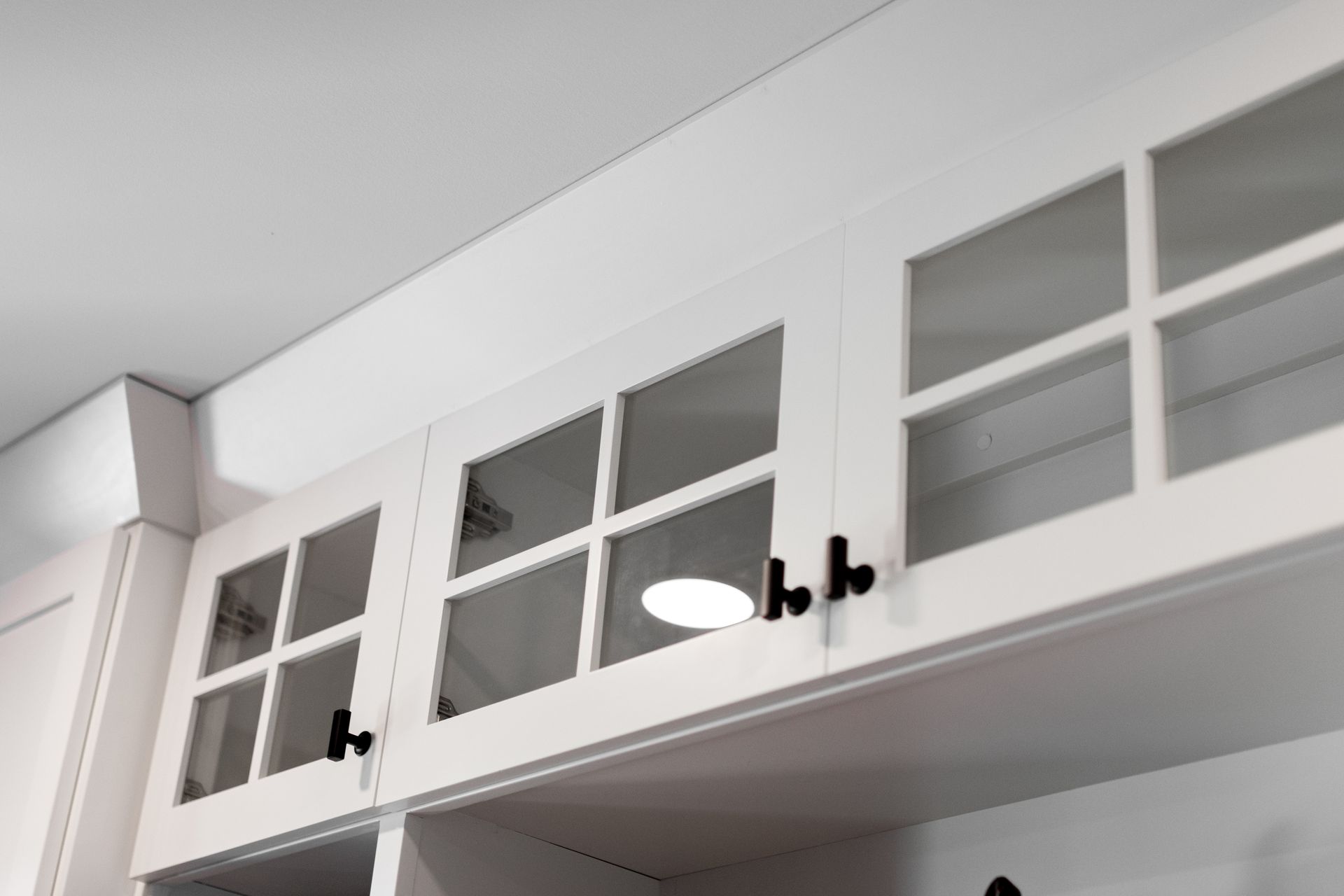 White kitchen cabinets with glass doors and black hardware.