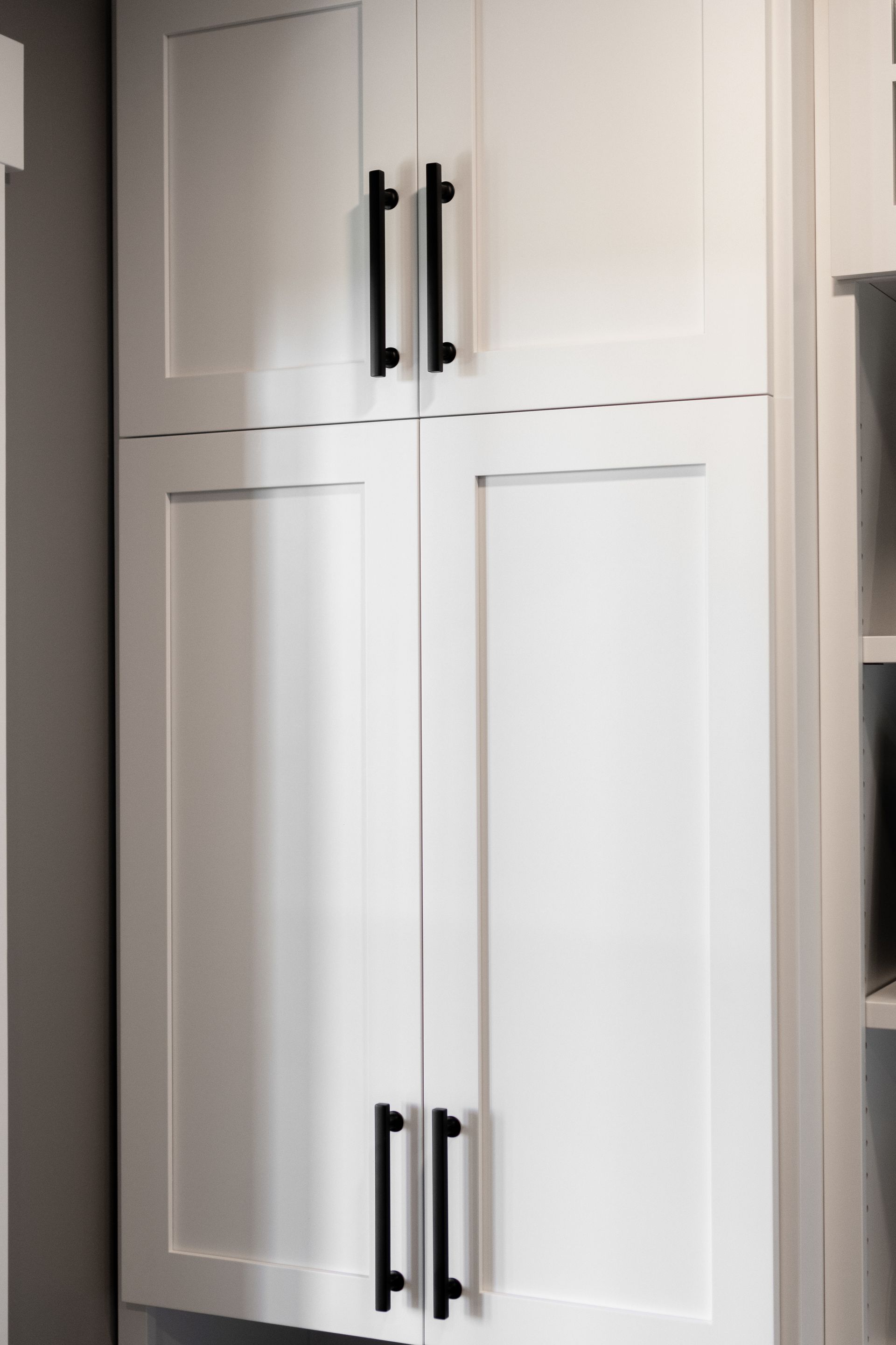 White kitchen cabinet with black handles.