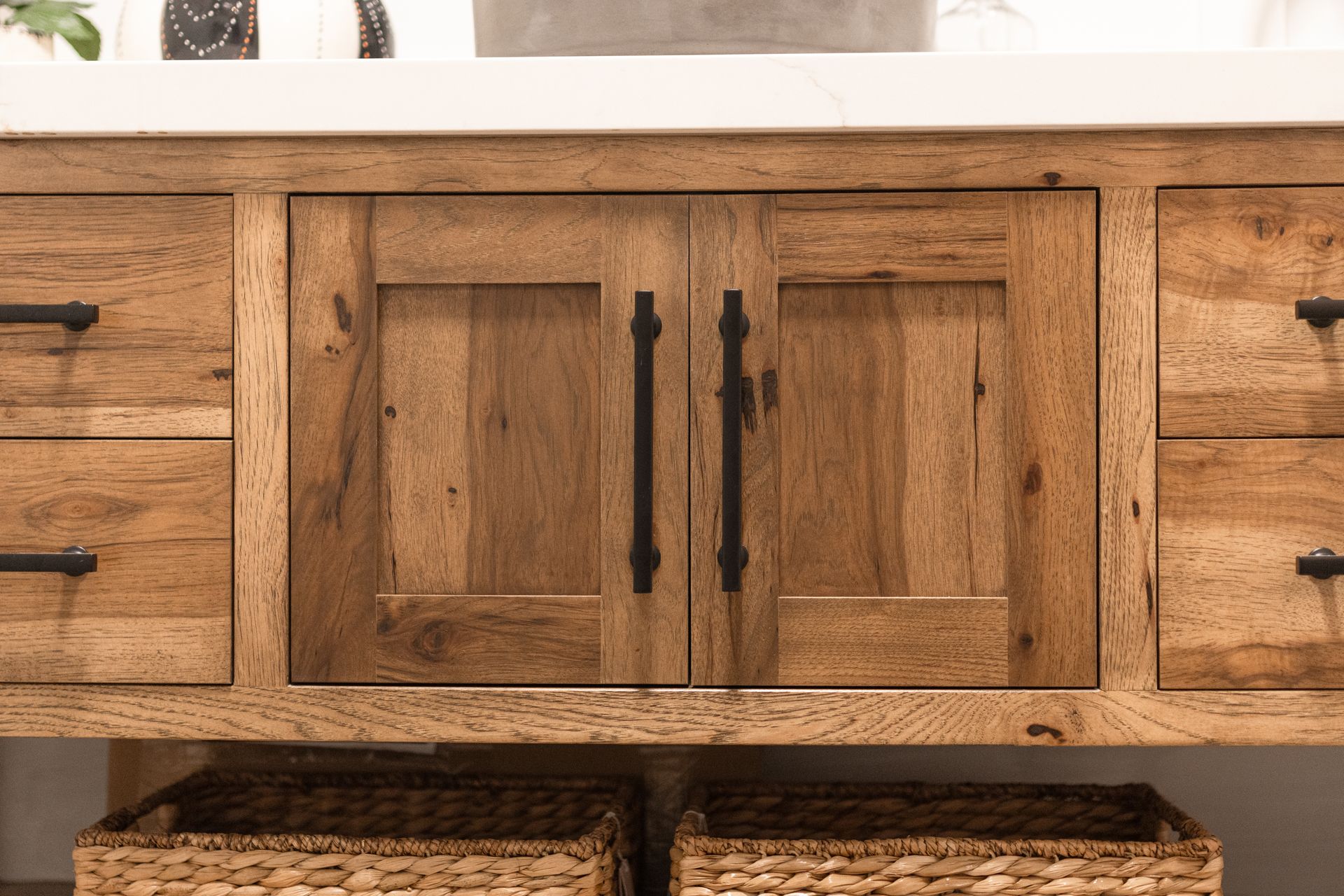 Wooden bathroom vanity with cabinet doors and drawers, black hardware.