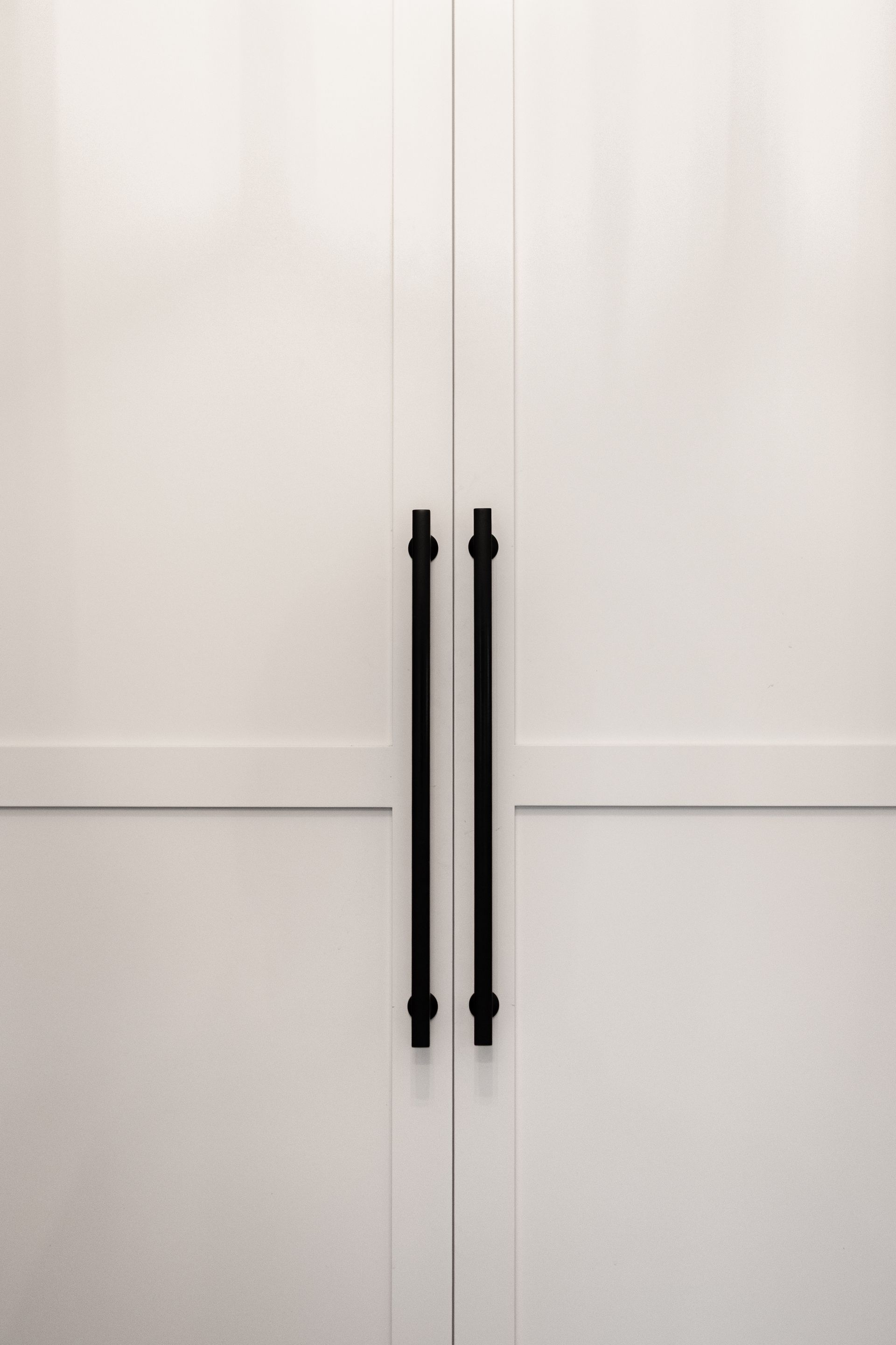 White cabinet doors with black bar handles.