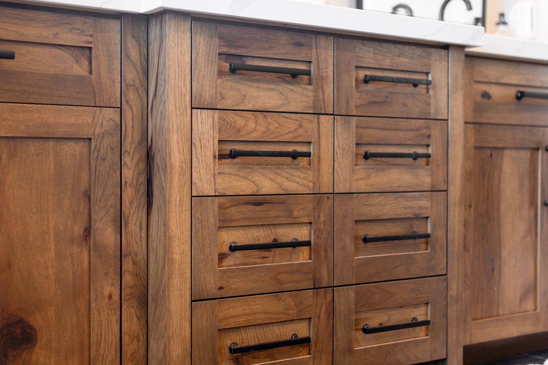Close-up of wooden kitchen drawers with black hardware.