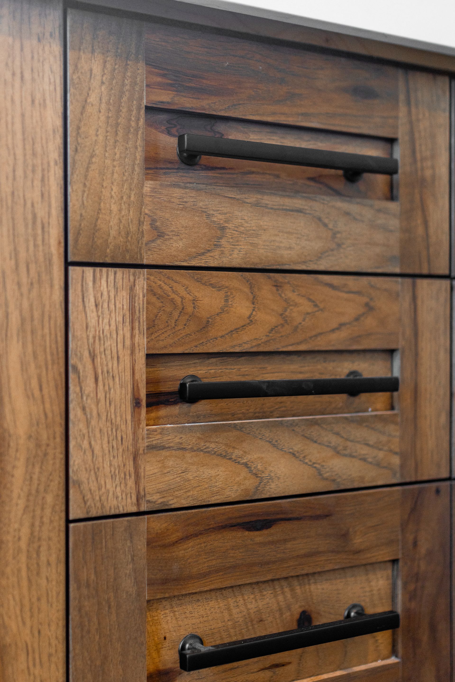 Wooden cabinet with three drawers and black handles.