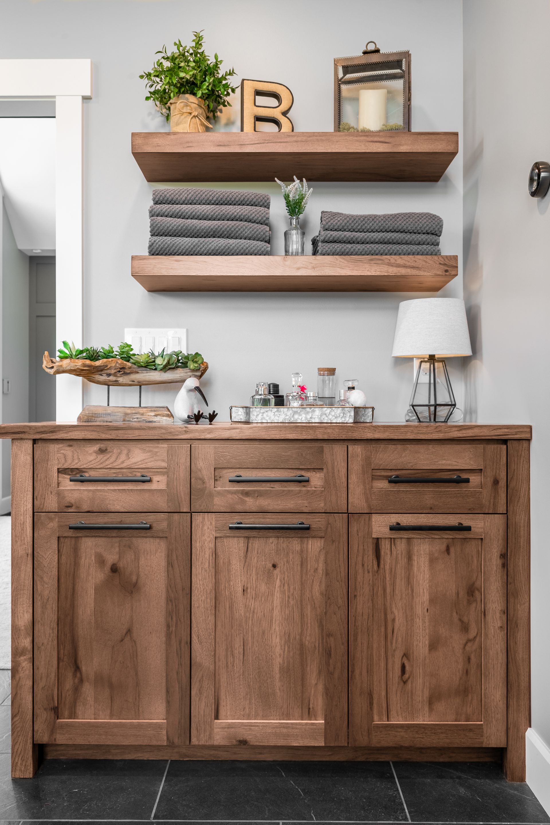 Wooden vanity with shelves, towels, and decorations in a bathroom.