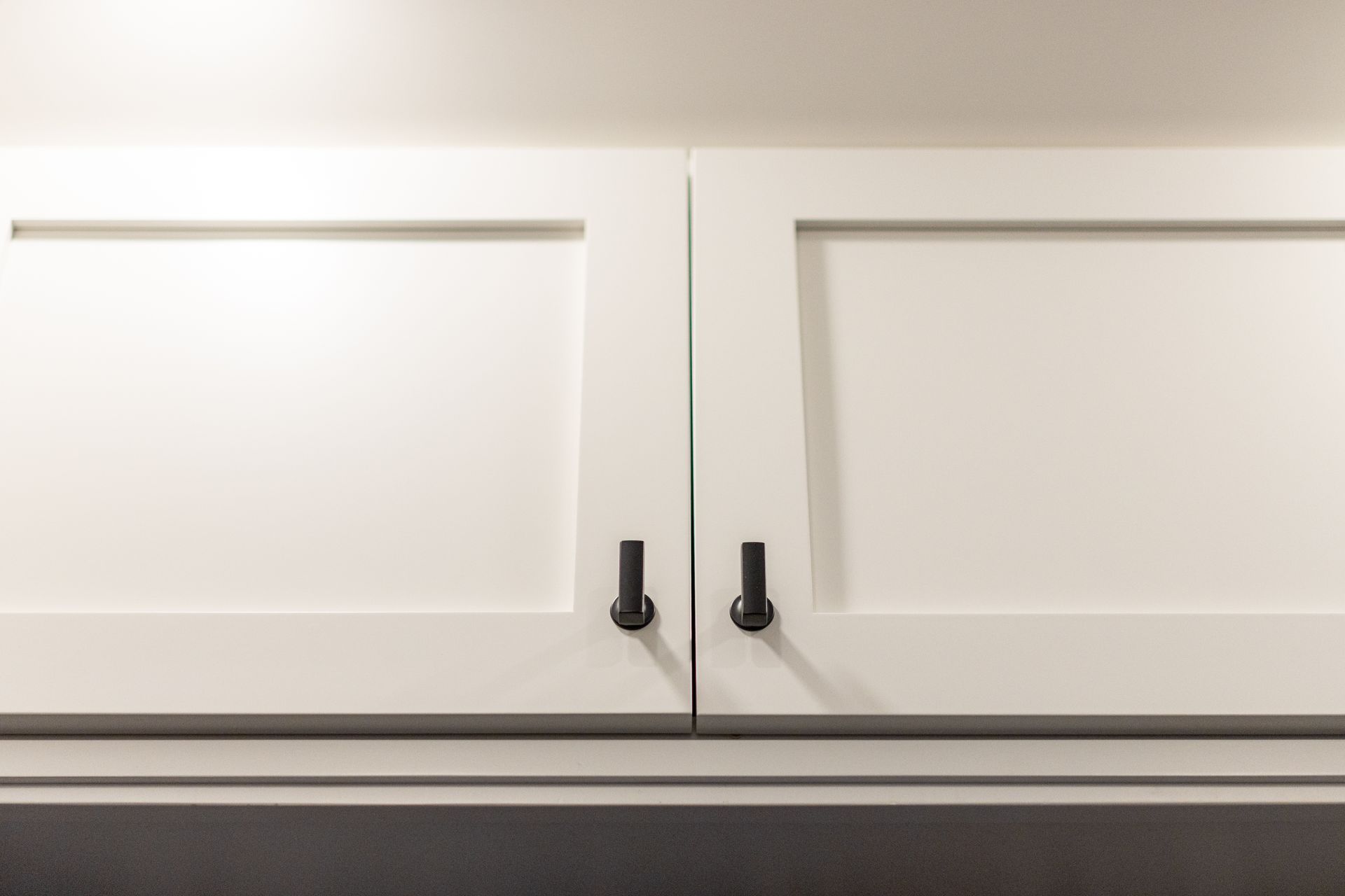 White kitchen cabinets with black handles.