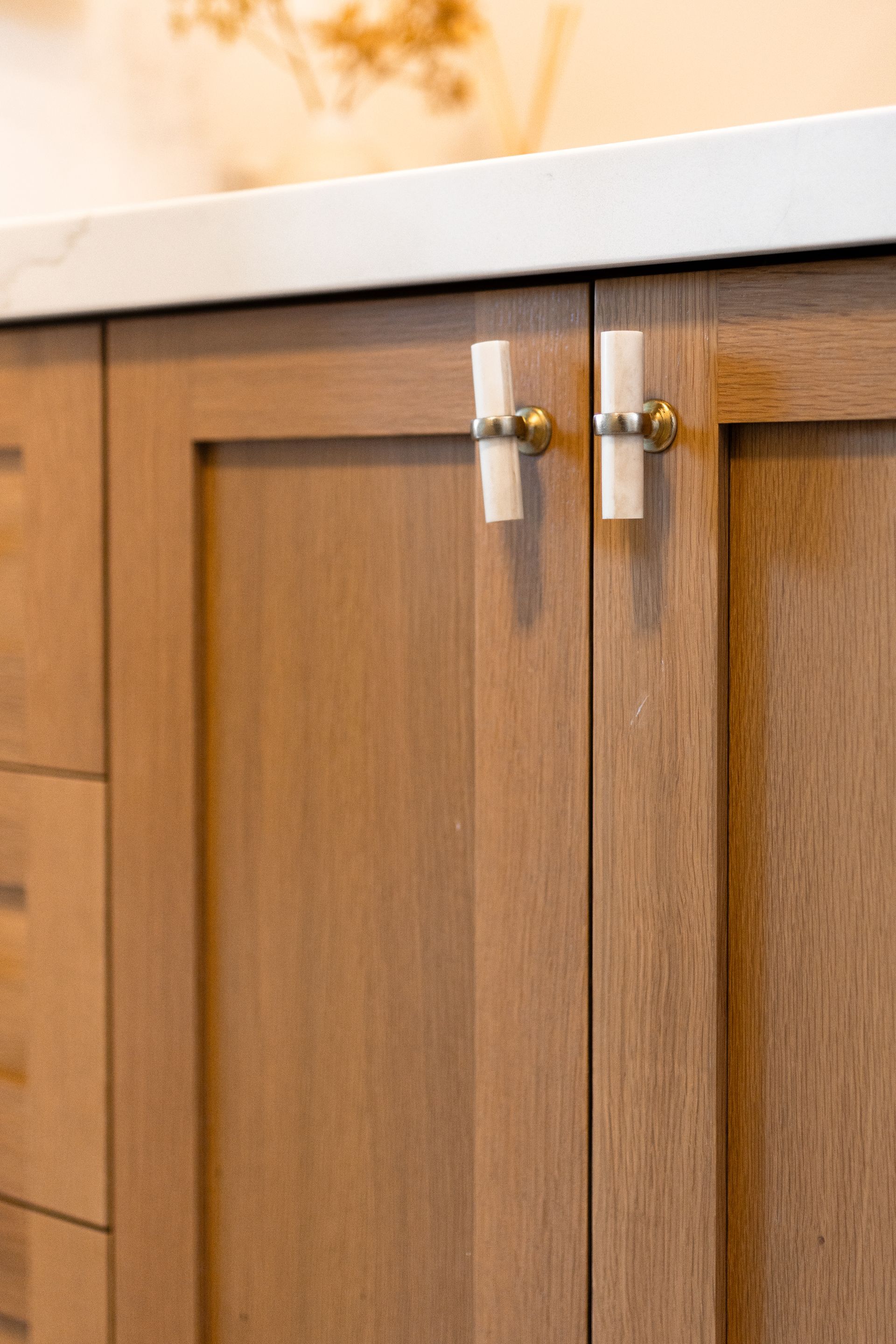 Wooden cabinet doors with brass and white knobs beneath a white countertop.
