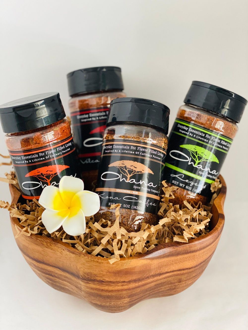 Four jars of spices are sitting in a wooden bowl.