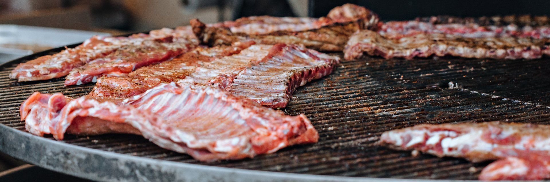 A bunch of meat is cooking on a grill.