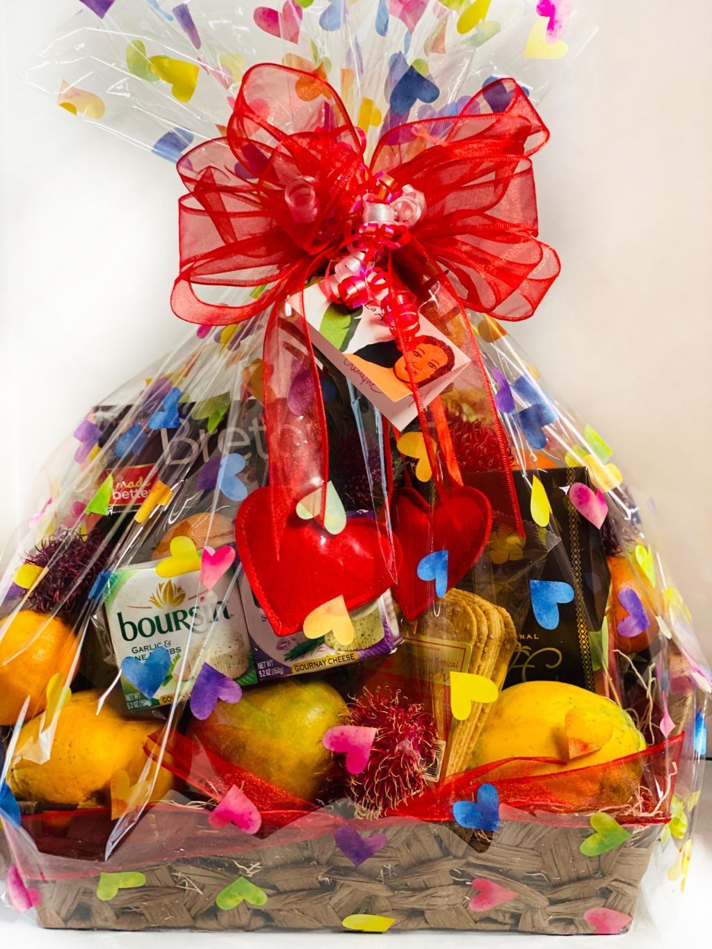 a fruit basket wrapped in plastic with a red bow .