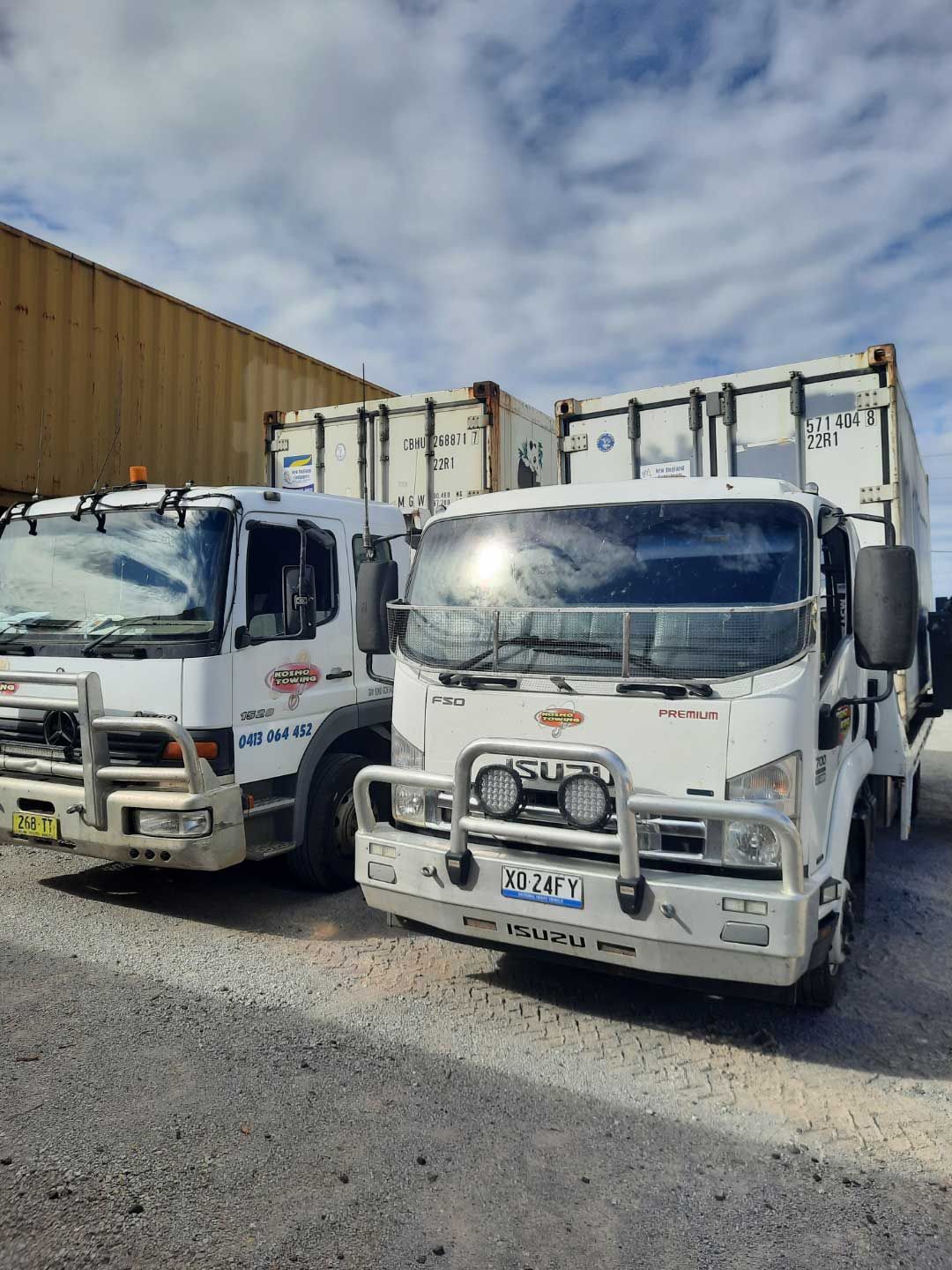 Two white trucks are parked next to each other on the side of the road.