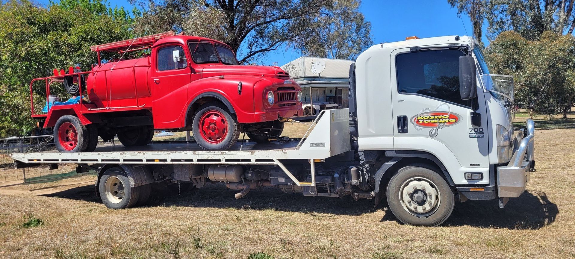 A red truck is sitting on top of a white tow truck.