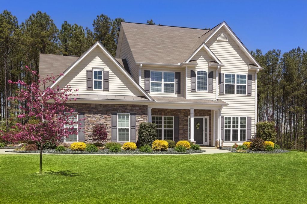 Two-story house with beige siding, stone accents.