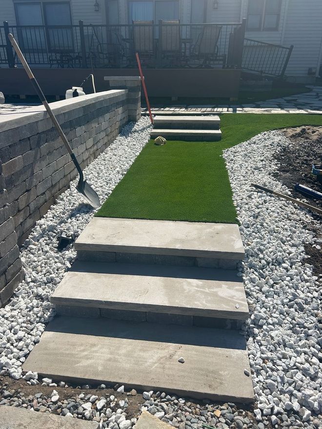 Stone steps leading up a slope with gravel and artificial turf.