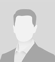 A professional headshot of a person wearing a formal suit and shirt against a plain, light gray background.