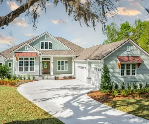 A large house with a driveway leading to it is surrounded by trees and grass.