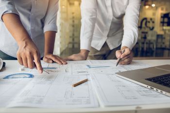 Two men are looking at a blueprint on a table.