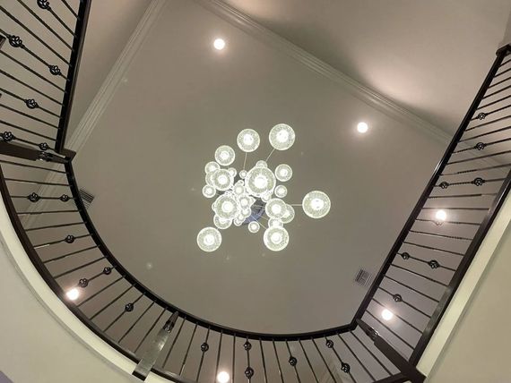 Looking up at a curved staircase and bright chandelier in a modern interior