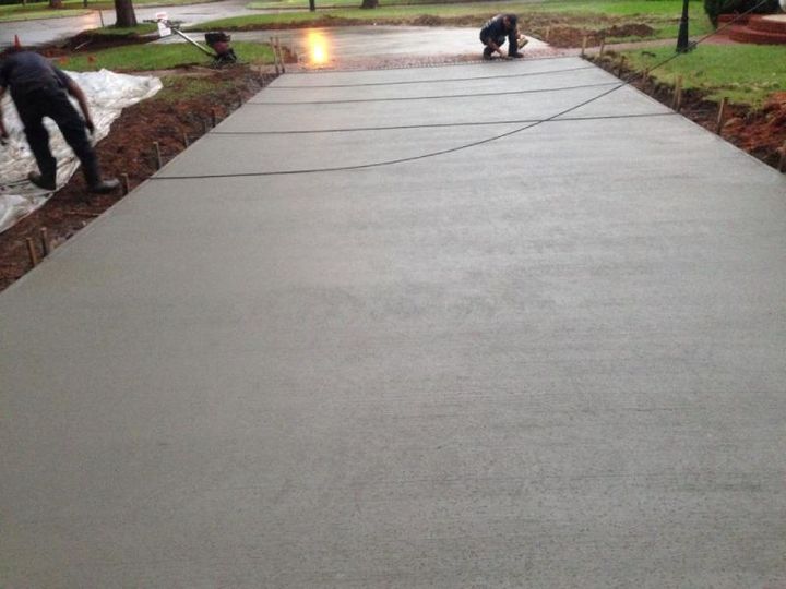 Two men are working on a concrete driveway.