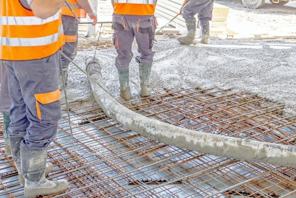 A group of construction workers are pouring concrete on a construction site.