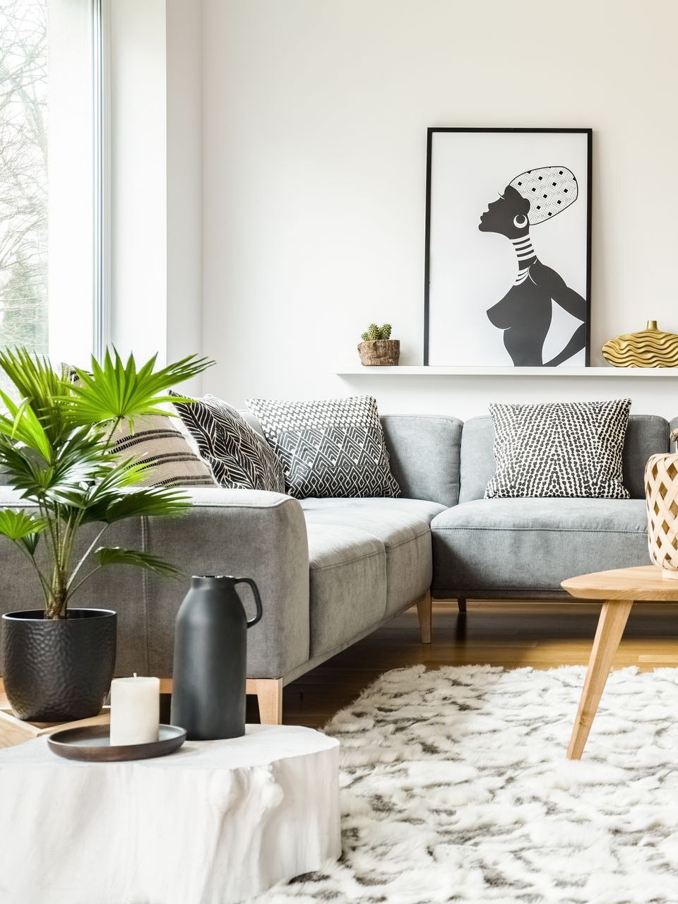 A living room with a couch , coffee table , plants and a picture on the wall.