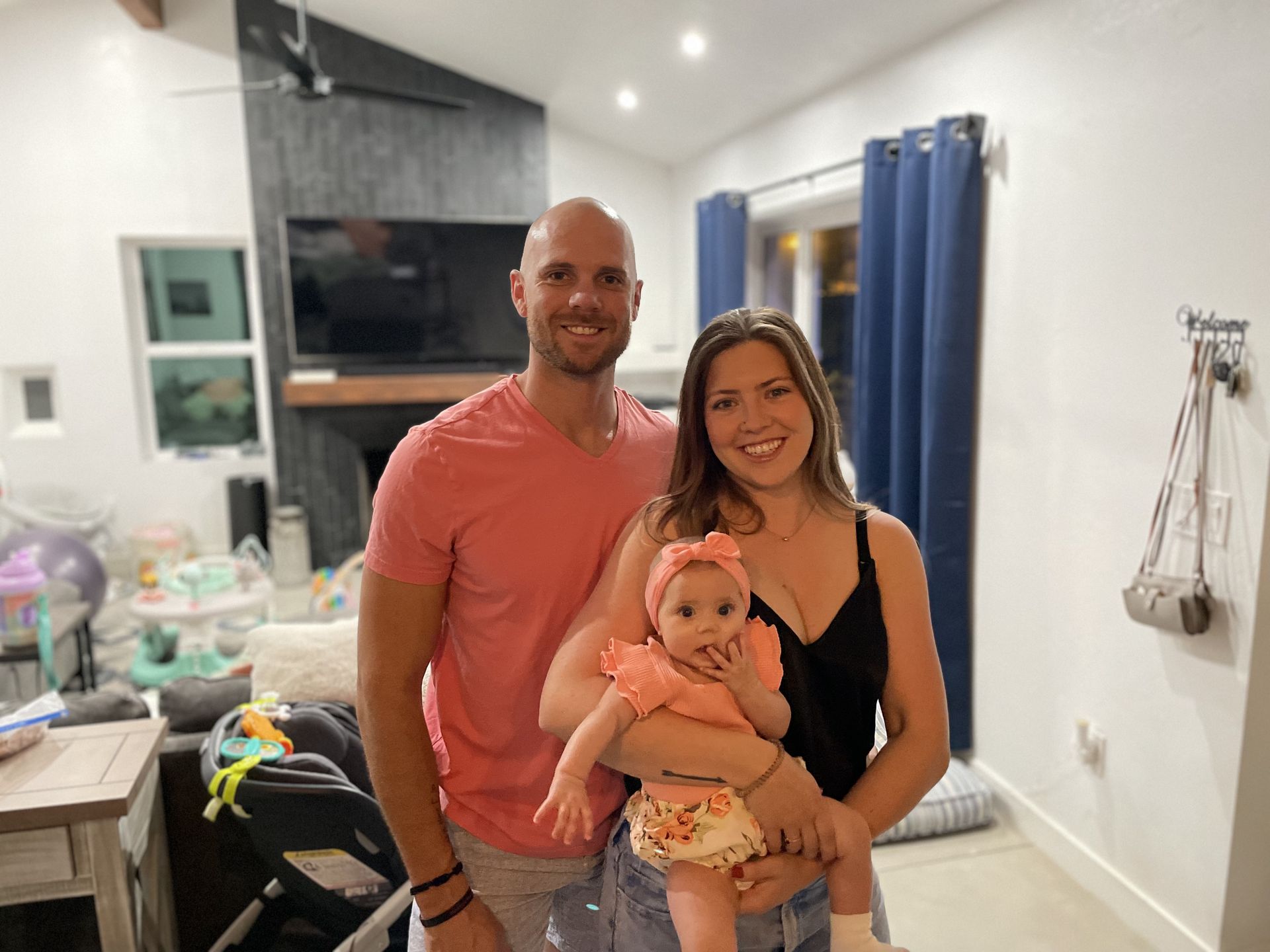 A man and woman are holding a baby in a living room.