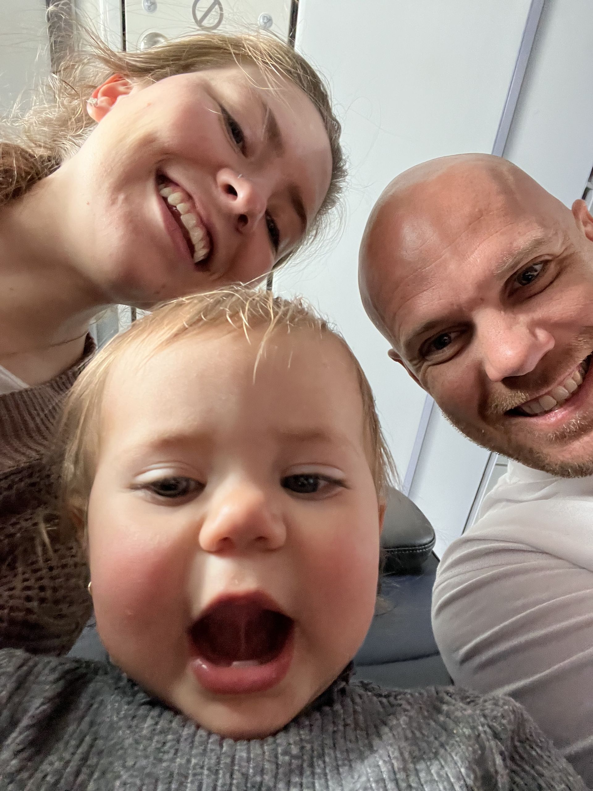 A man and a woman are posing for a picture with a baby.