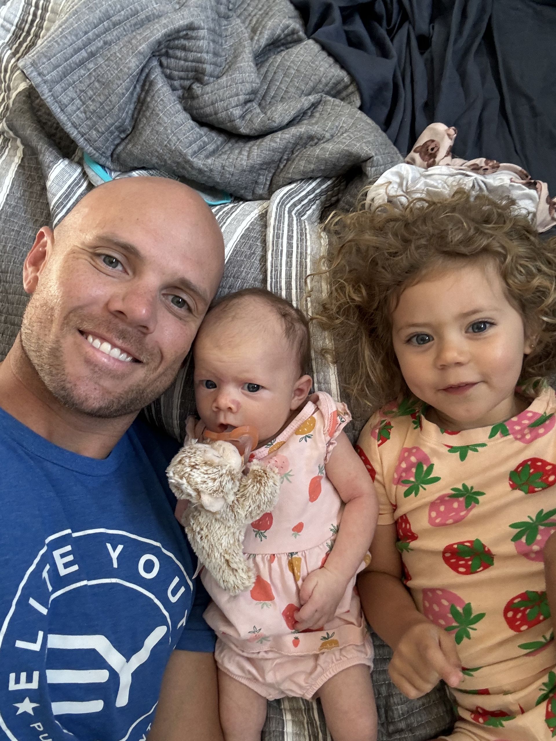 A man is laying on a bed with two children.