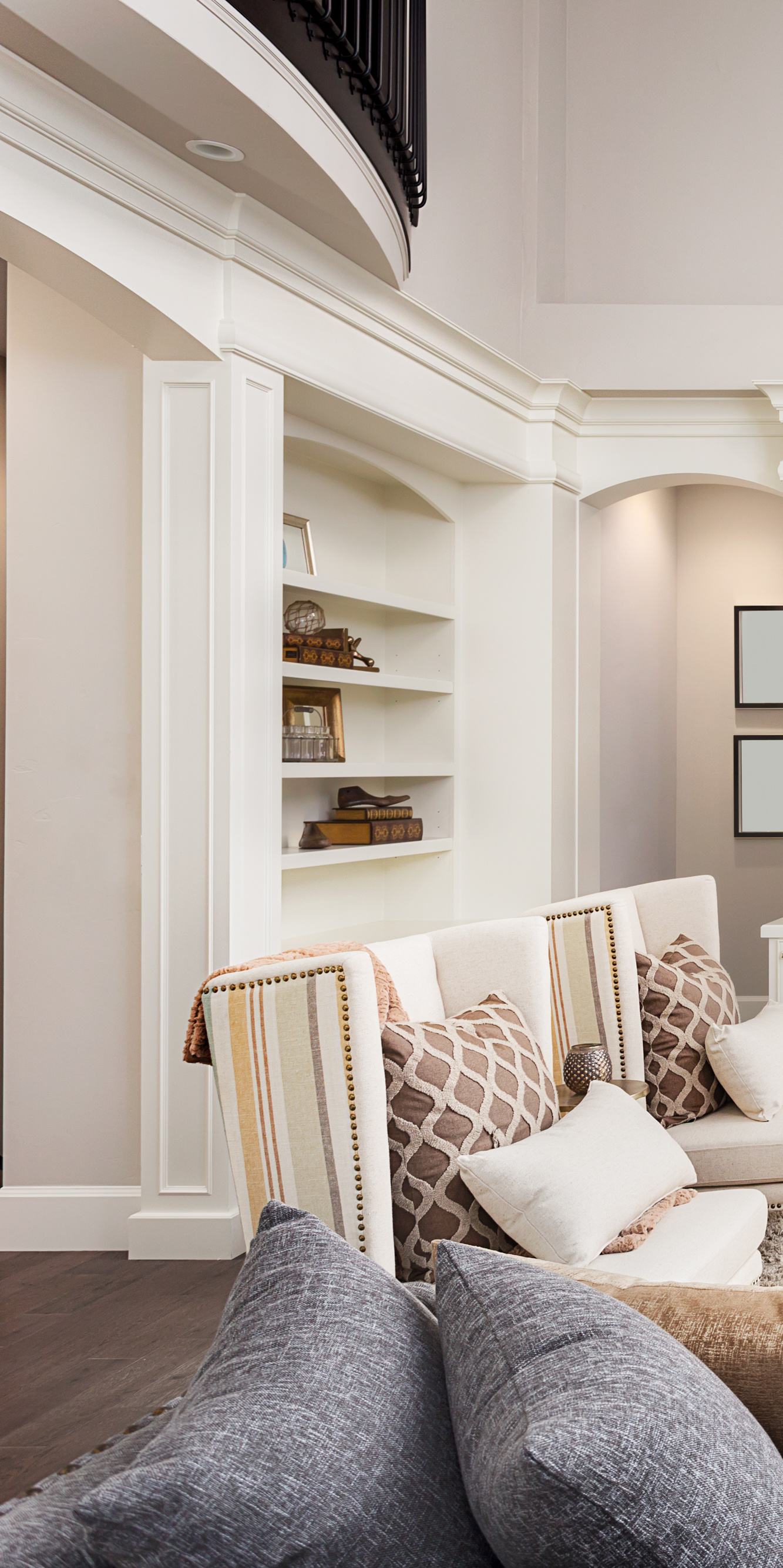 A living room with a couch , chairs , shelves and a balcony.
