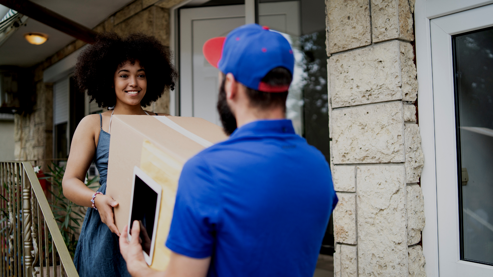 A delivery man is delivering a box to a woman.