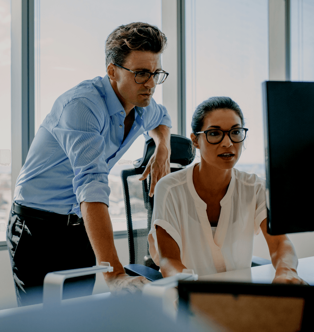 A man and a woman are looking at a computer screen.