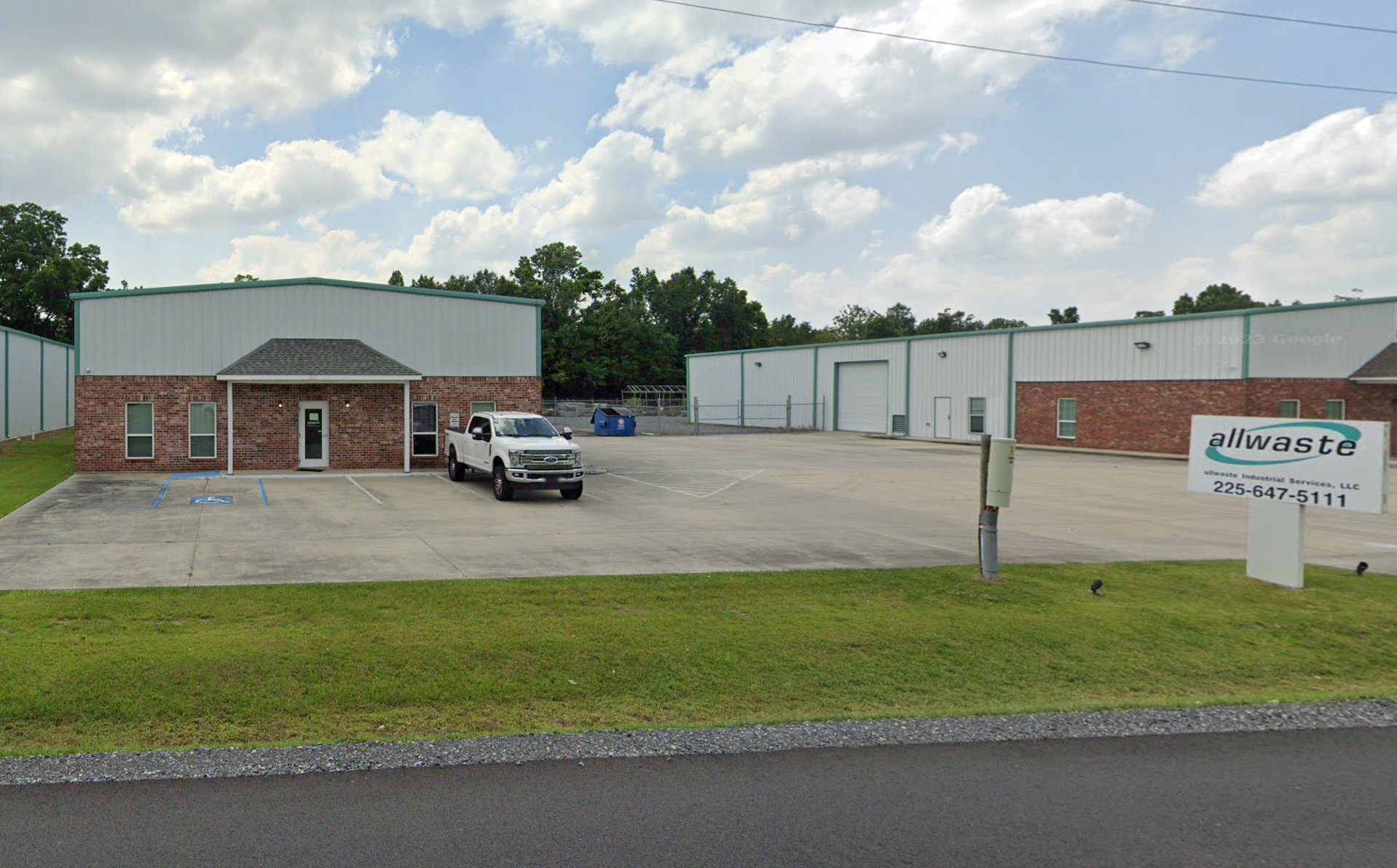 A white truck is parked in front of a brick building.