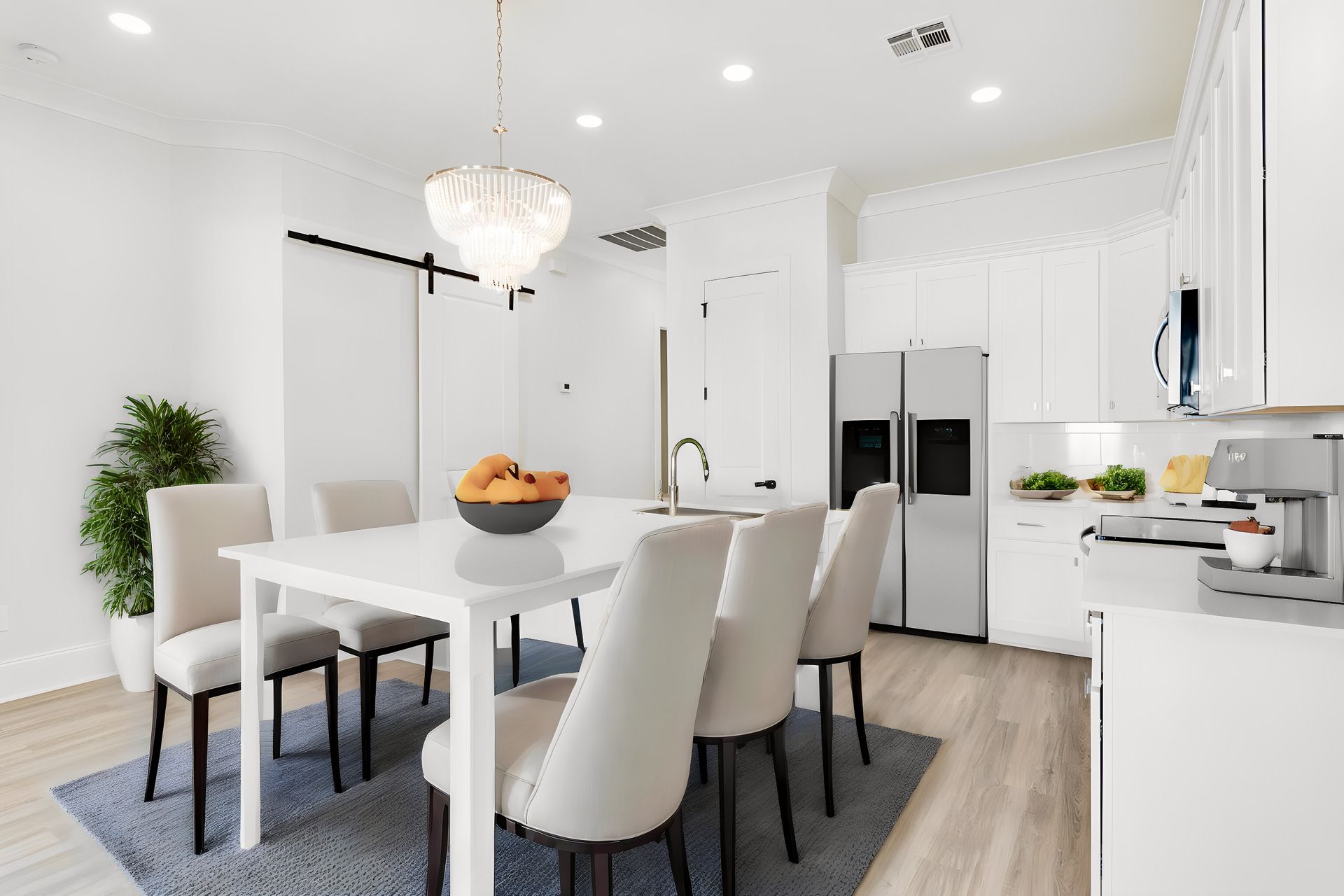 A dining room table and chairs in a kitchen with white cabinets.