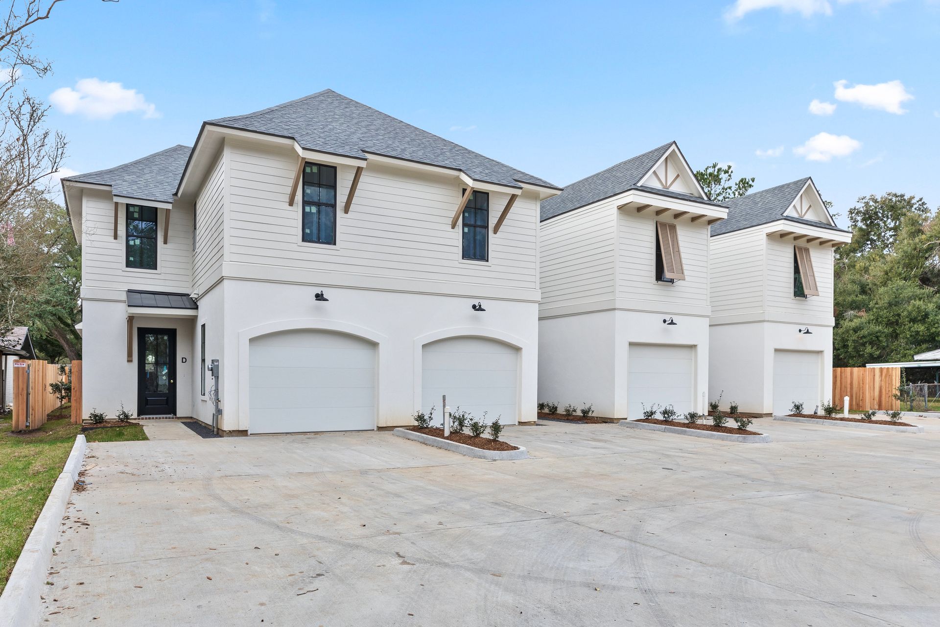 A row of white houses with garages and a concrete driveway.