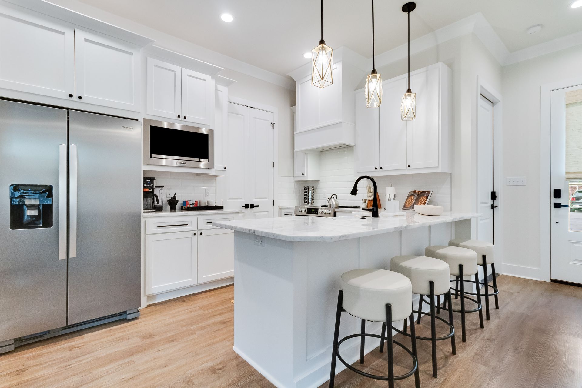 A kitchen with white cabinets , stainless steel appliances , and a large island.