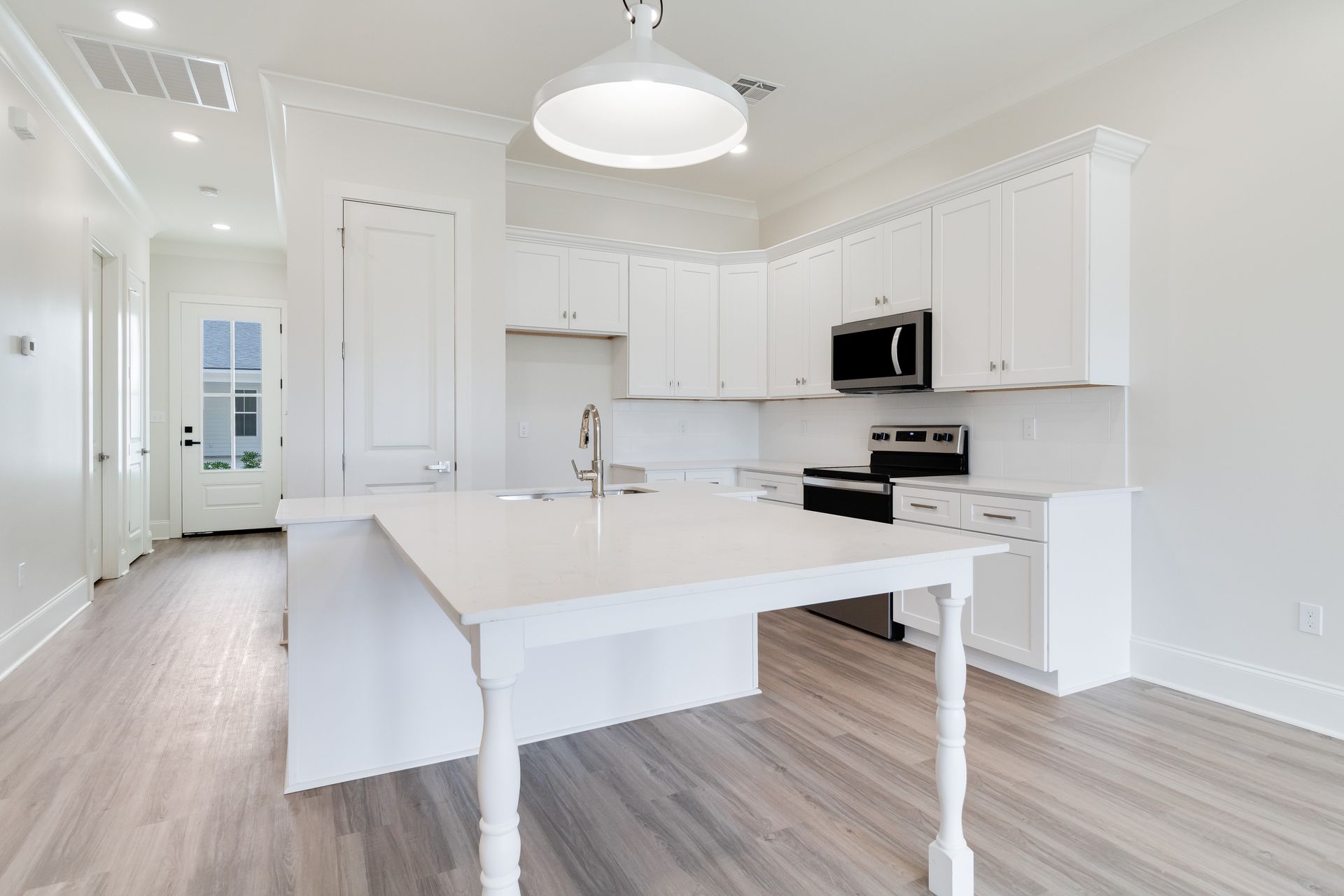 An empty kitchen with white cabinets and a large island.