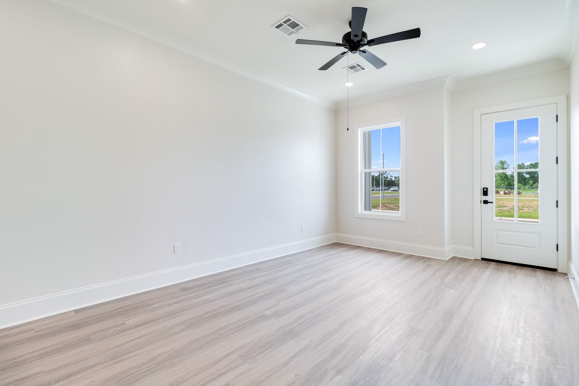 An empty living room with hardwood floors and a ceiling fan.