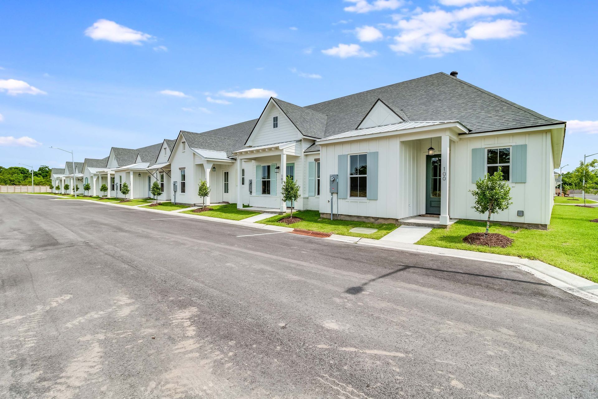 A row of white houses are lined up on the side of a road.