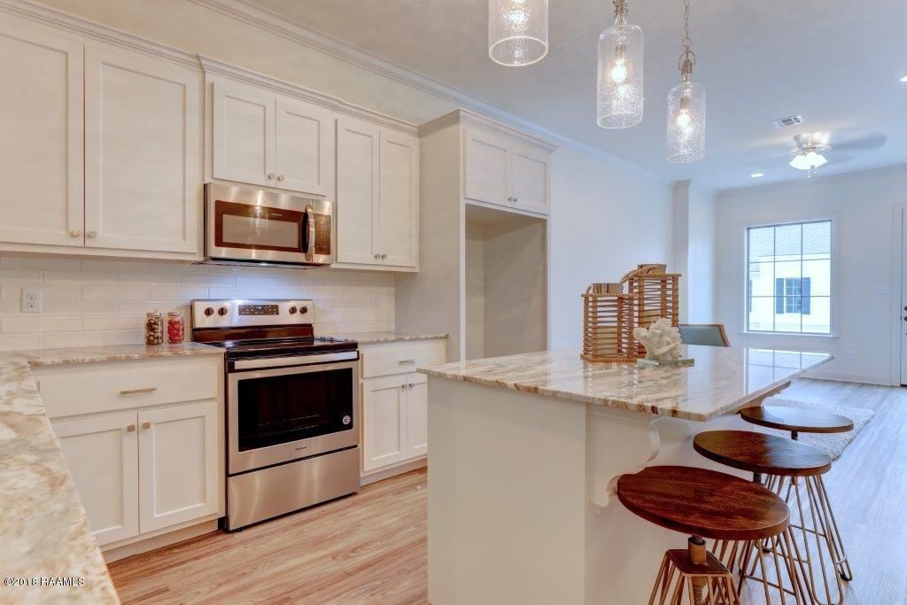 A kitchen with white cabinets , stainless steel appliances , and a large island.