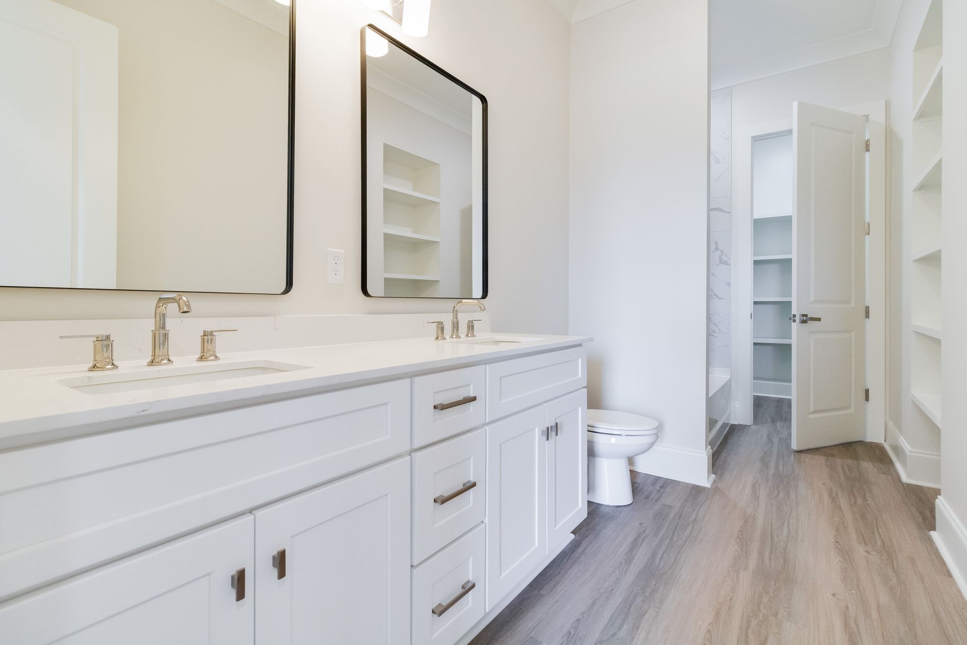 A bathroom with two sinks , a toilet , and a walk in closet.