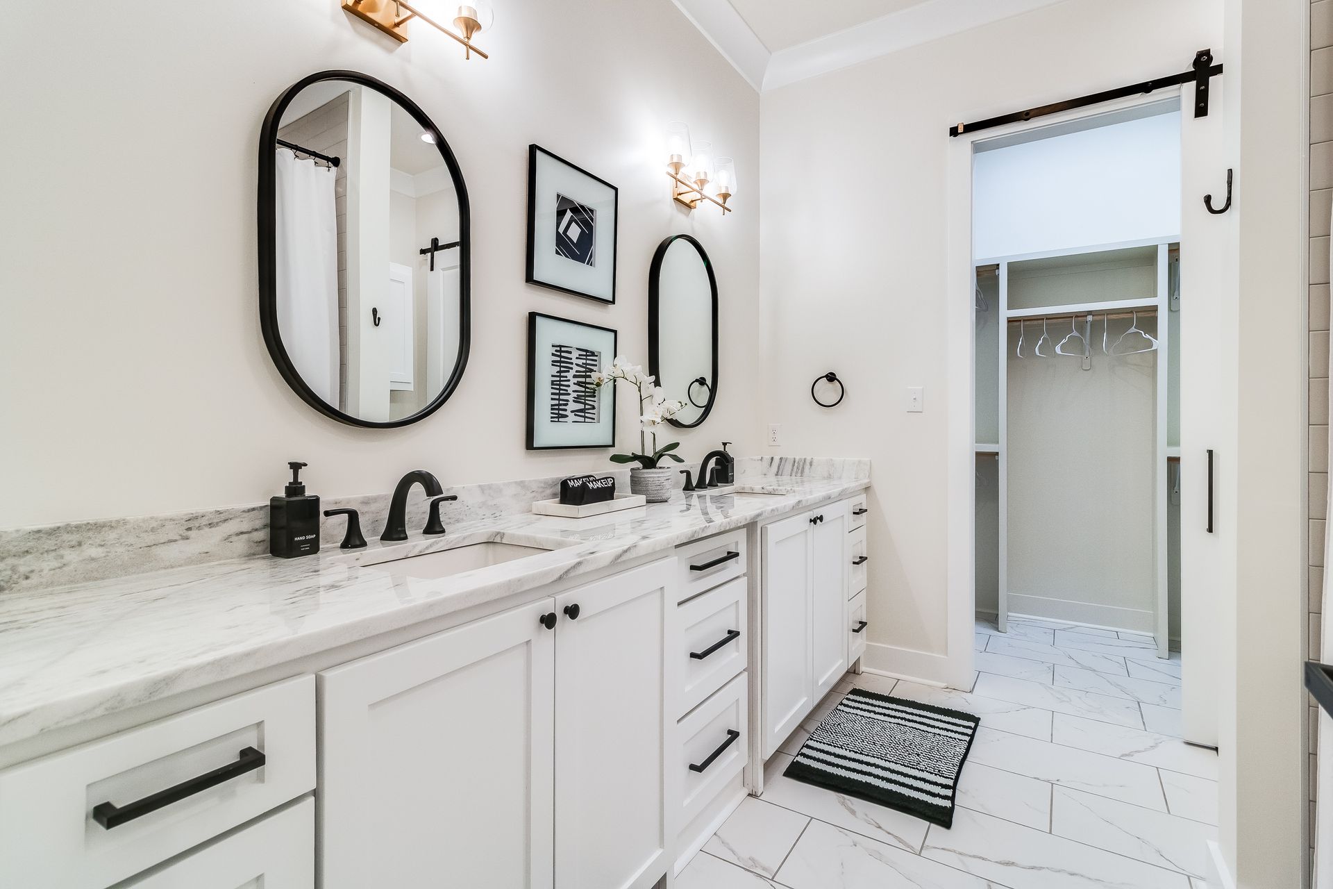 A bathroom with two sinks , two mirrors and a walk in closet.