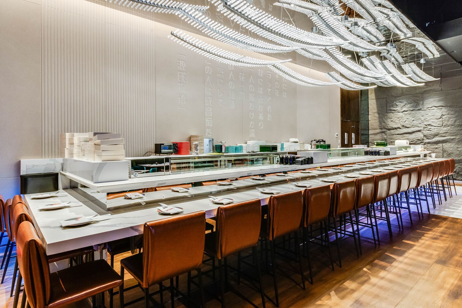 A long table and chairs in a restaurant with a chandelier hanging from the ceiling.