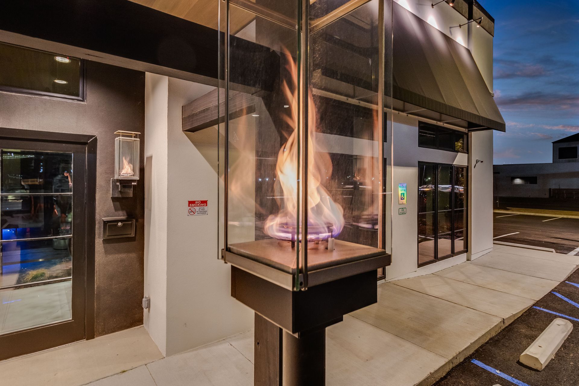 A lantern with a fire inside of it is outside of a building.