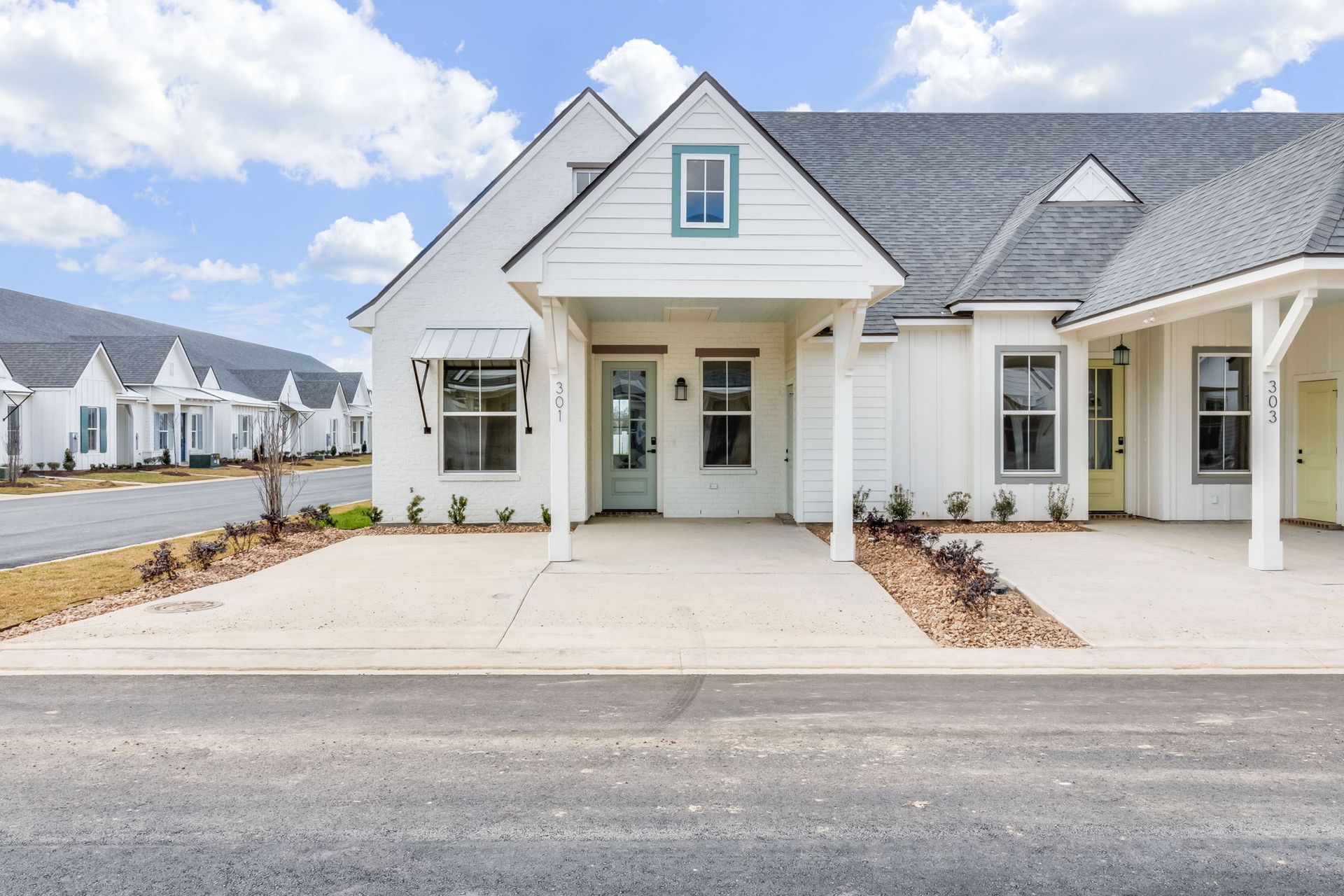 A white house with a blue door and a gray roof is for sale.